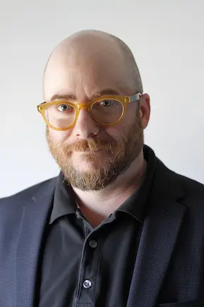 A bald man with glasses and a beard.